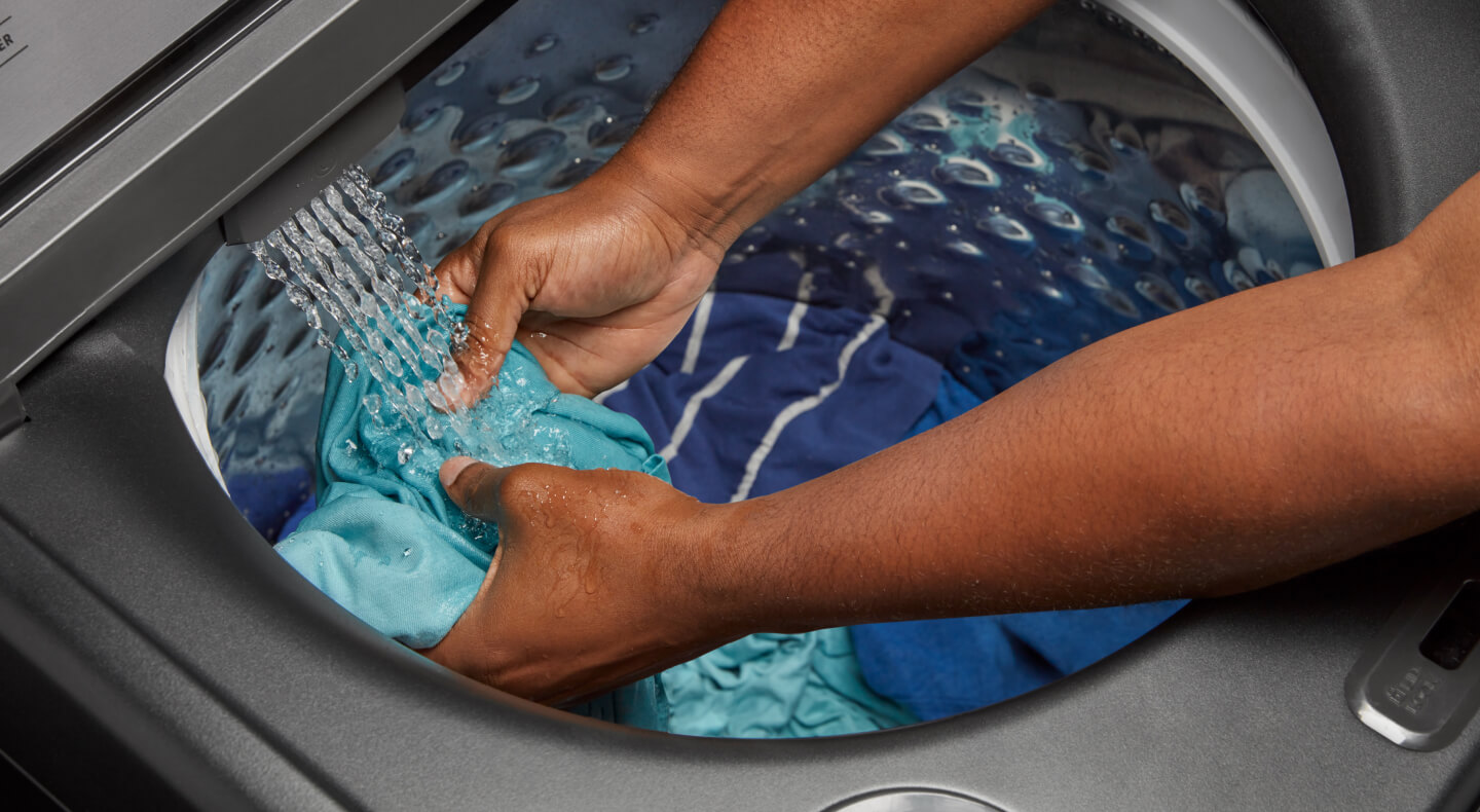 Person pretreating a stain inside the drum of a Maytag® top load washer