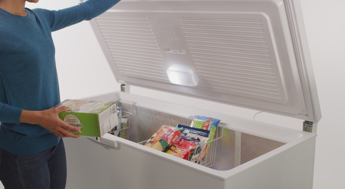A person taking food out of a Maytag® chest freezer