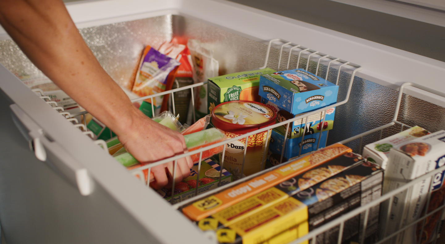 A closeup of person reaching into the interior of a Maytag® freezer