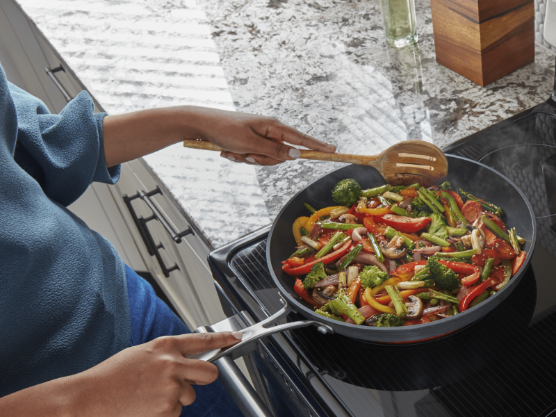 Person cooking vegetables in a skillet