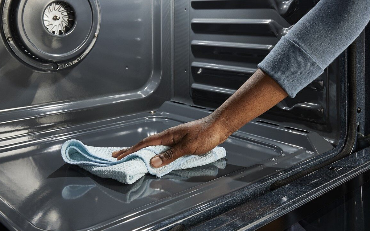 Hand wiping down the inside of an oven with a dry cloth