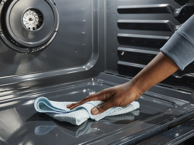 Hand wiping down the inside of an oven with a dry cloth
