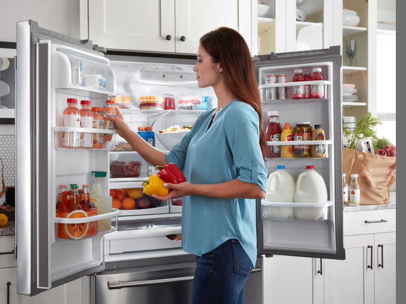 Person loading door shelves of a Maytag® French door refrigerator with beverages