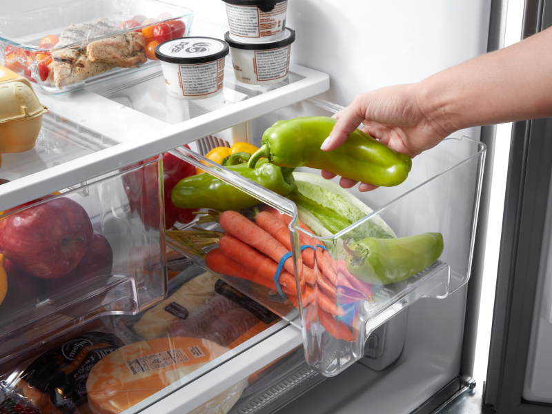 Person placing peppers into a crisper drawer