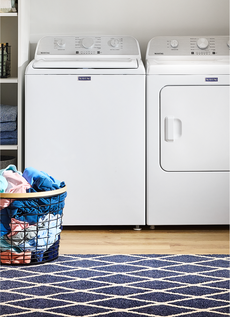 A laundry basket in front of a Maytag® washer and dryer pair.