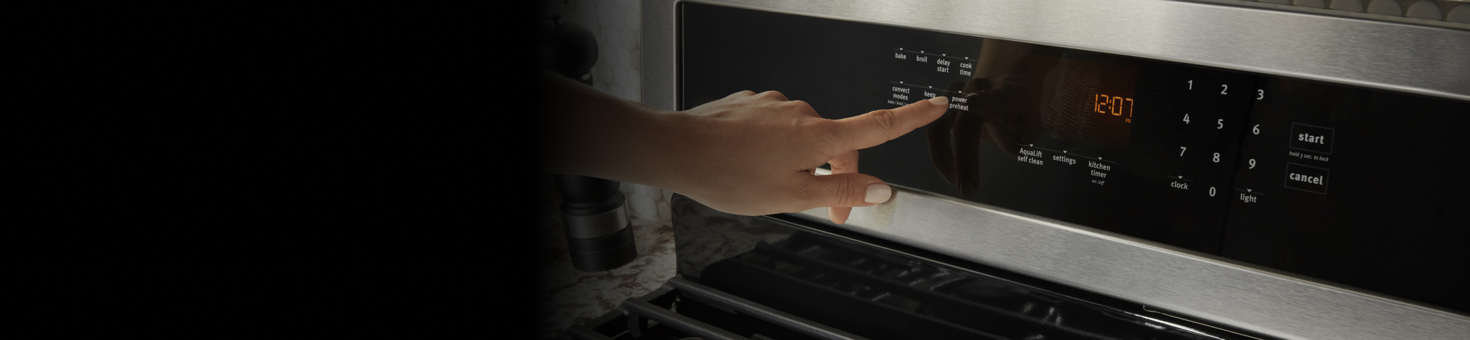 Hand touching the Power Preheat button on a range control panel