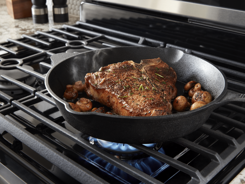 T-bone steak simmering on a Maytag brand gas cooktop