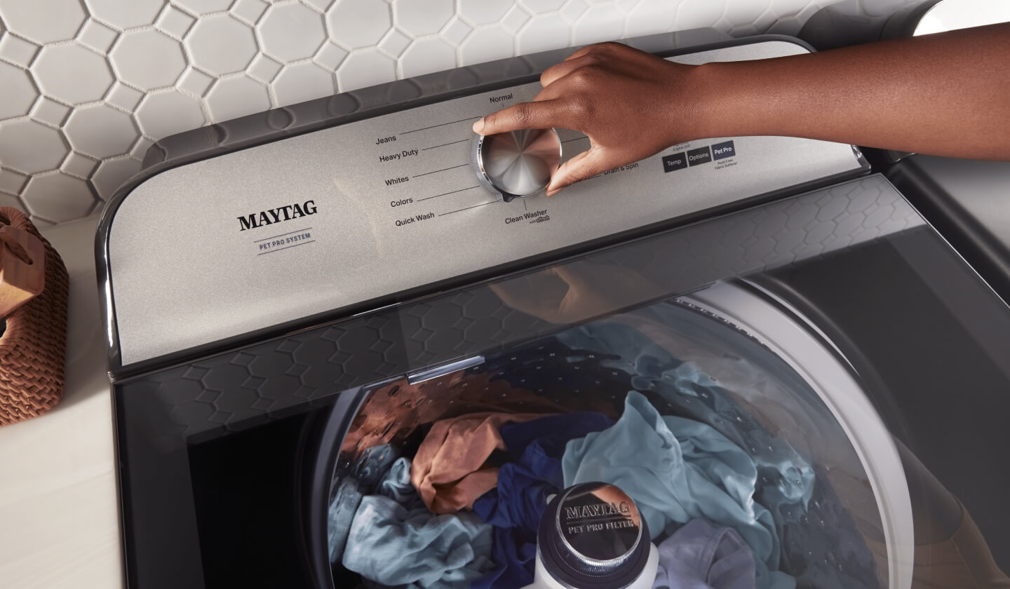 Someone adjusting the control panel of their washer