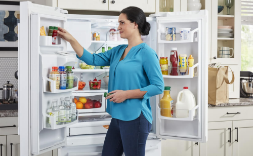 Person placing food in side door of refrigerator 