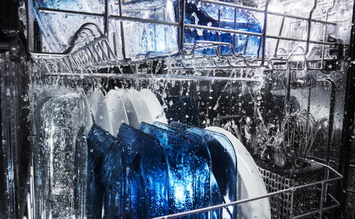 Blue and white dishes inside a dishwasher with water spraying on them