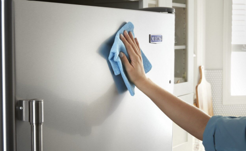 Person cleaning a stainless steel appliance 