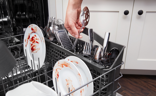 Hand loading silverware into a dishwasher