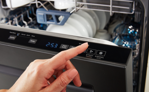 Finger hovering over “Start” button on dishwasher control panel
