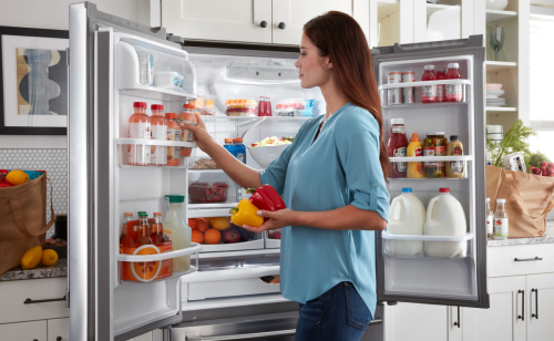 Woman loading drinks in the refrigerator door