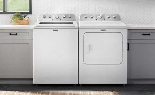 White front load laundry pair in between grey cabinets in a laundry room
