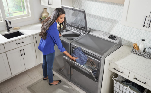 A person switching clothes between a washer and a dryer
