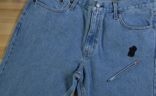 A pen on a pair of jeans stained with ink