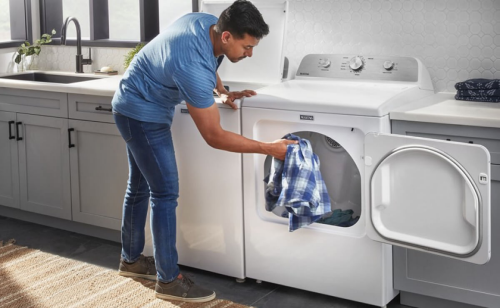 A man taking a shirt out of a Maytag® dryer