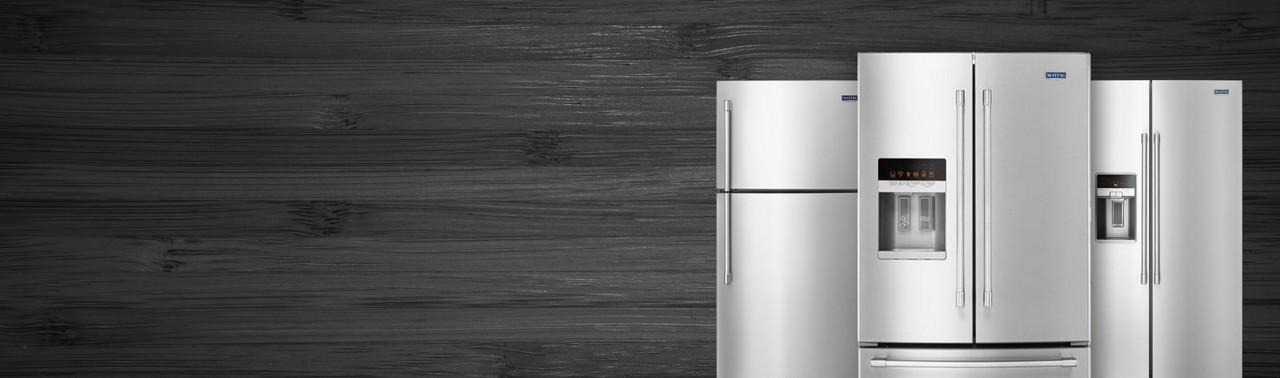 Three stainless steel refrigerators on a dark background.