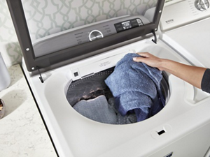 Hand loading a top load washer with towels and blankets