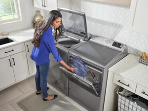 Person moving a load of laundry from a washer to the dryer