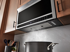 Steam venting from a boiling pot on the stove into an over-the-range microwave