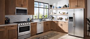 A stainless steel Maytag® kitchen suite installed in a kitchen with light wood cabinets.