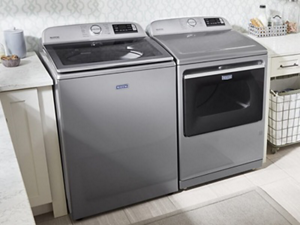 Maytag® top load washer and dryer in between cream cabinetry in a laundry room