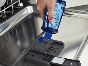 Person adding dishwasher detergent to a detergent dispenser