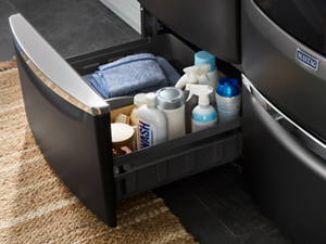 A Maytag® washer pedestal with laundry supplies