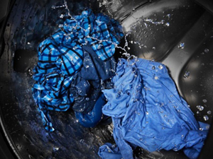 Blue garments in a top load washer drum filled with water