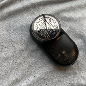A fabric shaver on a pair of sweatpants with fabric pilling