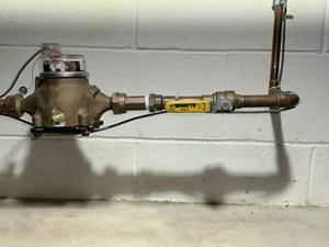 Water shut-off valve and pipes along cinderblock wall