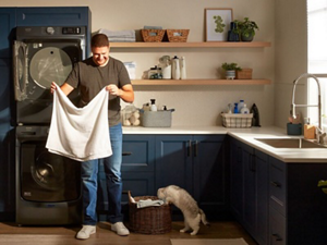 Person folding laundry in laundry room with cat