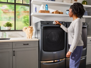 Person setting washer settings with cat on counter next to washer