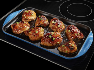 Chicken thighs in a pan on an electric cooktop