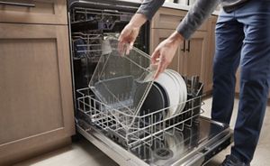 A person putting the air fry basket in a dishwasher.